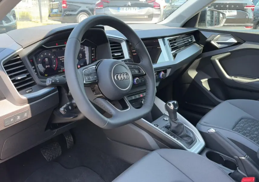 Intérieur Audi A1 Sportback 2026 vu côté conducteur, volant cuir multifonction et console centrale moderne.