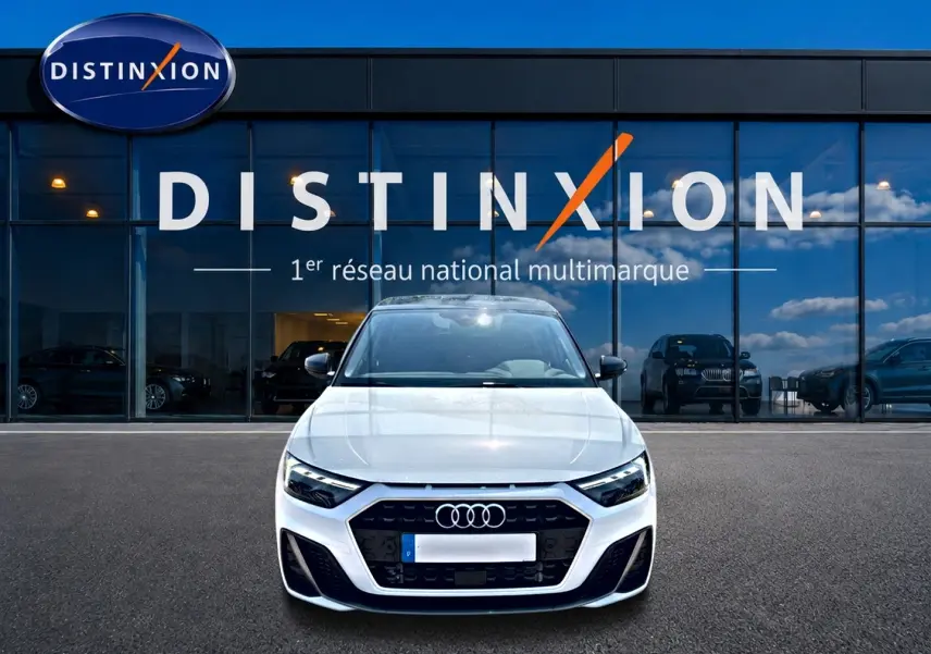 Audi A1 Sportback blanc et noir vue de face, avec calandre noire et logo Audi visible devant un showroom Distinxion.