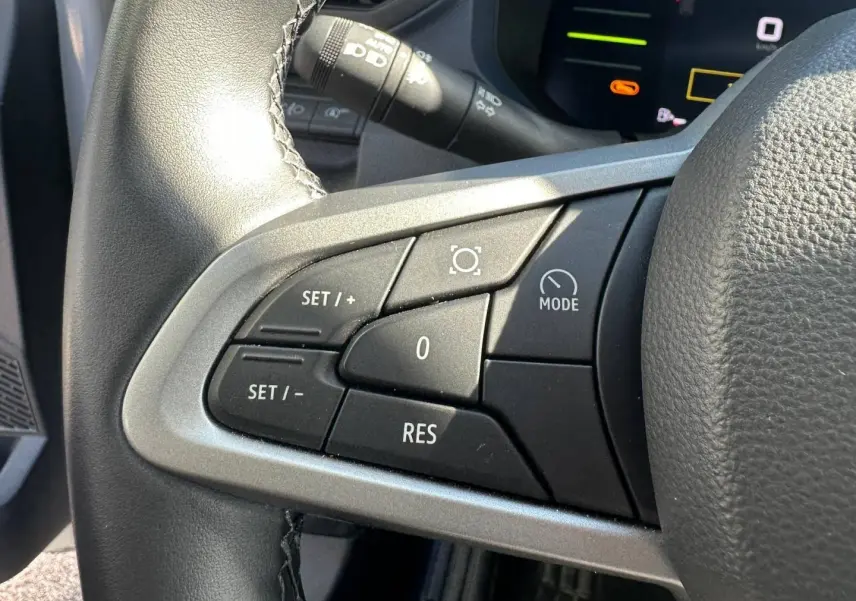 Gros plan sur les commandes du volant multifonction noir et gris du Dacia Duster 2025, version Journey Sandstone.