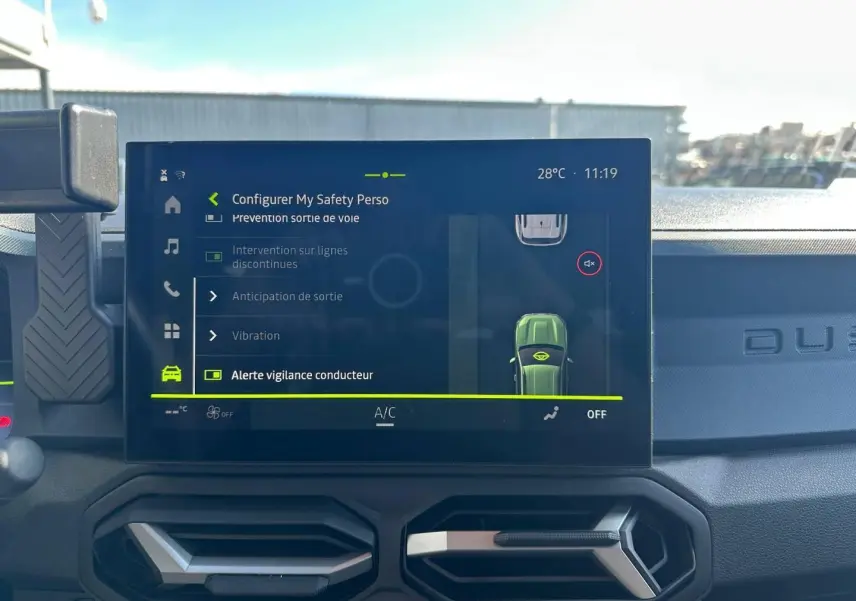 Vue intérieure du tableau de bord du Dacia Duster 2025 avec écran tactile affichant les réglages de sécurité, ambiance sobre.