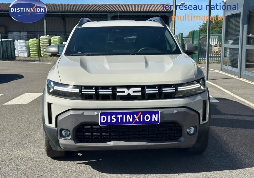 Vue frontale d'un Dacia Duster 2025 couleur Sandstone avec calandre noire et phares LED fins.