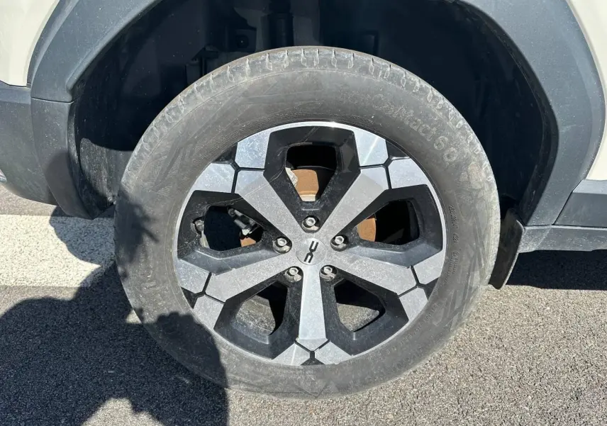 Gros plan sur la roue avant gauche du Dacia Duster 2025 couleur Sandstone avec jante alu noire et grise.