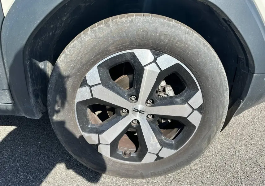 Gros plan sur la jante alu noire et grise du Dacia Duster 2025, version Sandstone, avec pneu Continental.