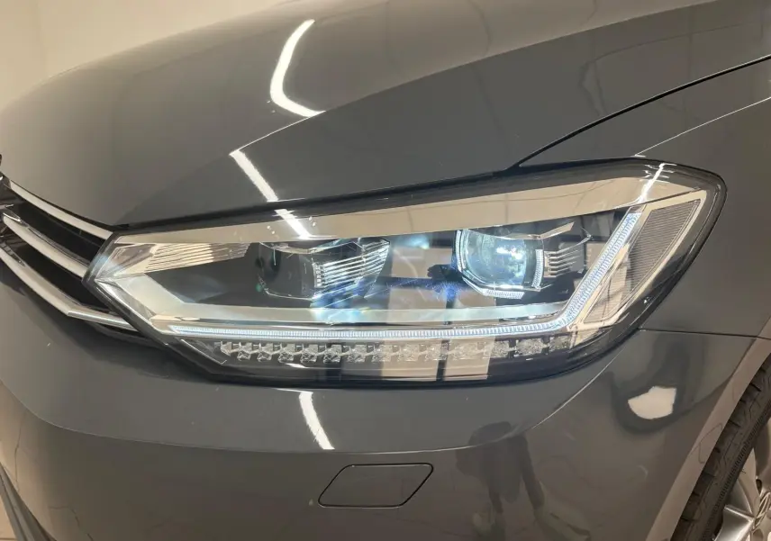 Gros plan sur le phare avant droit du Volkswagen Touran 2025 gris dauphin, mettant en valeur ses feux LED modernes.