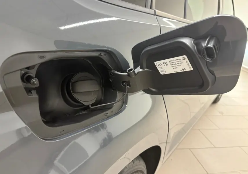 Ouverture de la trappe à carburant côté gauche d'un Volkswagen Touran gris dauphin 2025, essence.