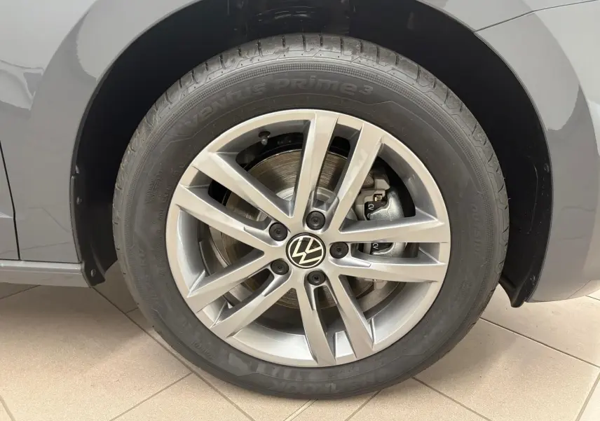 Gros plan sur la roue avant gauche du Volkswagen Touran gris Dauphin, mettant en valeur la jante alliage 17 pouces et le logo VW central.