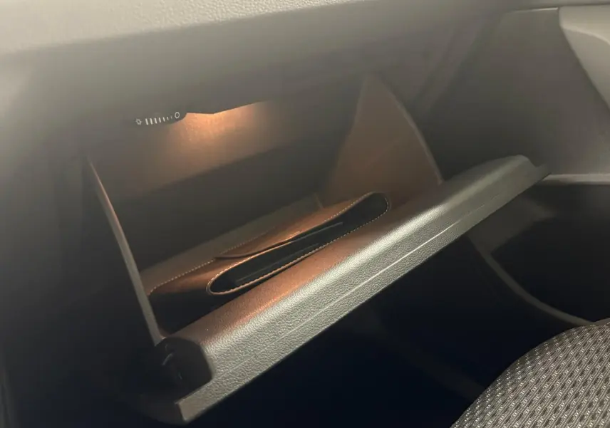 Gant de rangement ouvert éclairé dans l'habitacle du Volkswagen Touran gris Dauphin, côté passager.