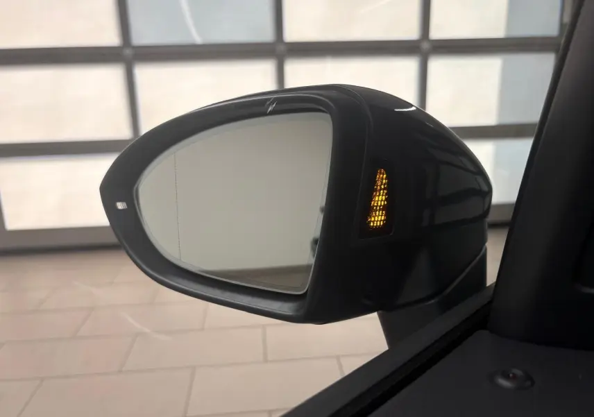 Rétroviseur extérieur droit du Volkswagen Touran gris dauphin 2025 avec clignotant orange allumé et angle intérieur visible.