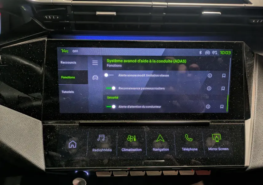 Vue rapprochée de l’écran tactile central du Peugeot 308 SW Hybrid 145 eDCS6 GT gris, affichant les fonctions d’aide à la conduite.