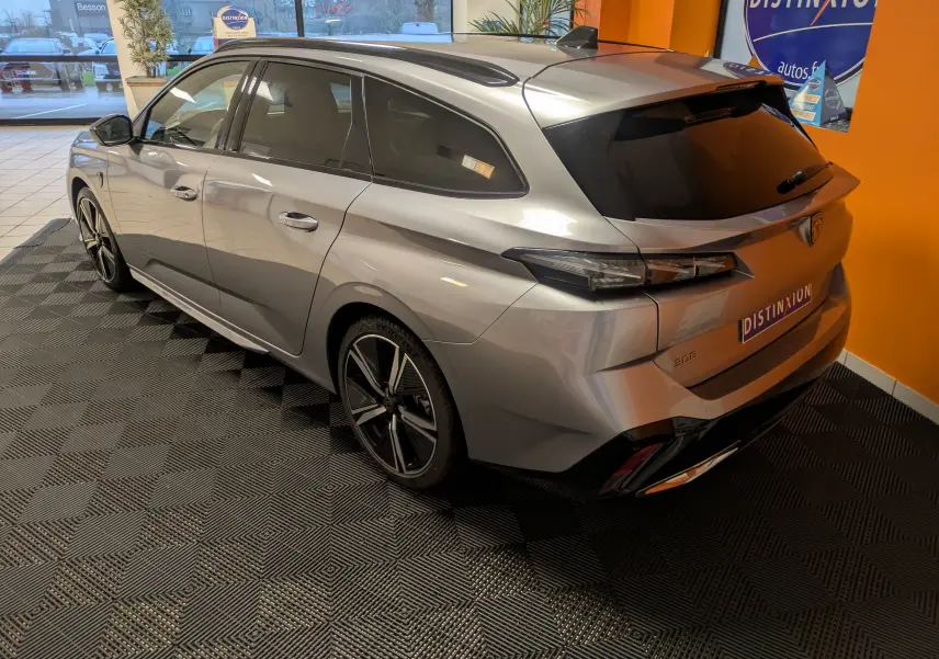 Vue 3/4 arrière droite d’un Peugeot 308 SW Hybrid gris métallisé, avec jantes alliage 18 pouces et vitres teintées.