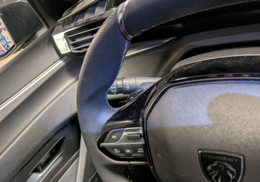 Intérieur côté conducteur de la Peugeot 308 SW Hybrid gris 2025, avec sellerie tri-matières et volant compact.