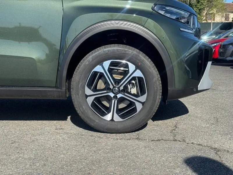 Gros plan sur la roue avant droite du Citroën C3 Aircross 2026 vert Montana avec jante alliage bicolore et partie avant blanche.
