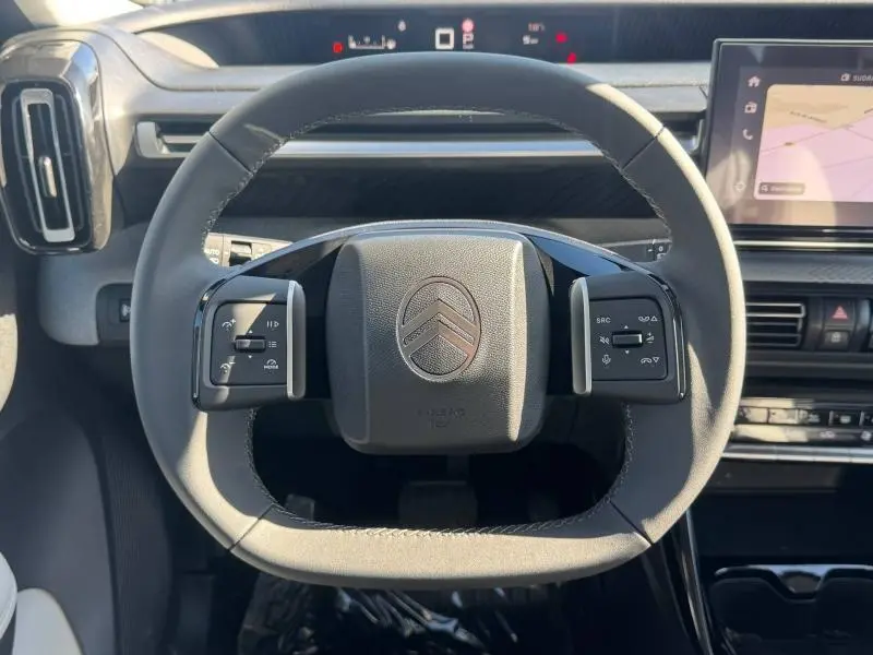 Vue frontale du volant noir du Citroën C3 Aircross 2026, avec commandes intégrées et tableau de bord digital en arrière-plan.