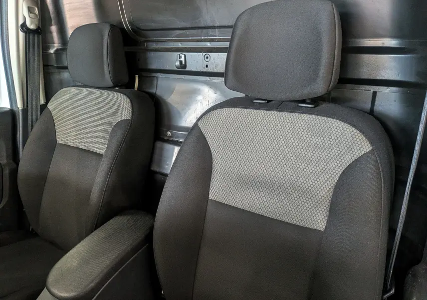 Gros plan sur les sièges avant en tissu noir et gris du Renault Kangoo Express Blanc Minéral, intérieur utilitaire visible.