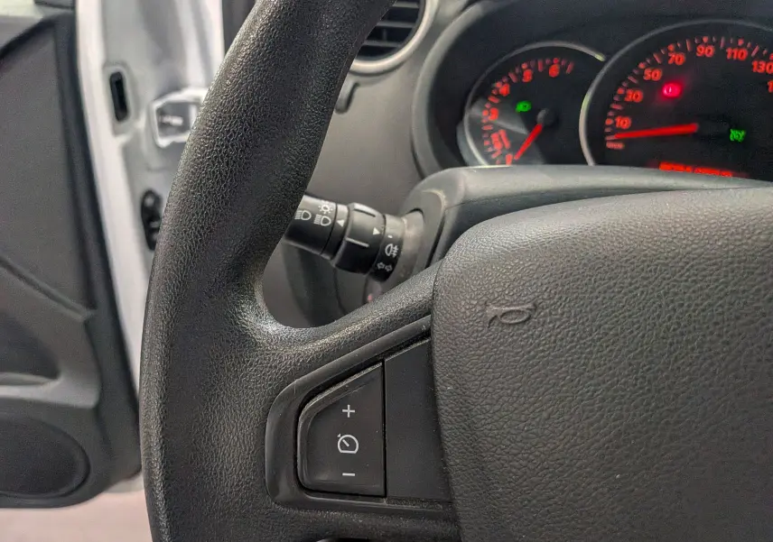 Gros plan sur le volant noir et le tableau de bord éclairé du Renault Kangoo Express blanc, version 2020.