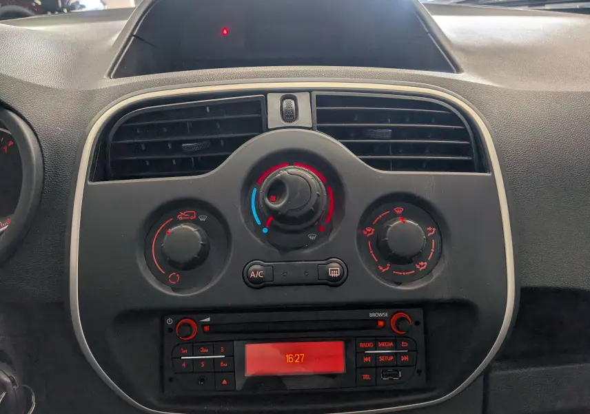 Vue rapprochée du tableau de bord central du Renault Kangoo Express blanc, avec commandes de climatisation et radio intégrée.