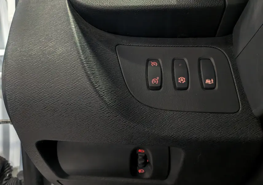 Gros plan sur les commandes noires du tableau de bord du Renault Kangoo Express 2020, avec boutons éclairés rouges.