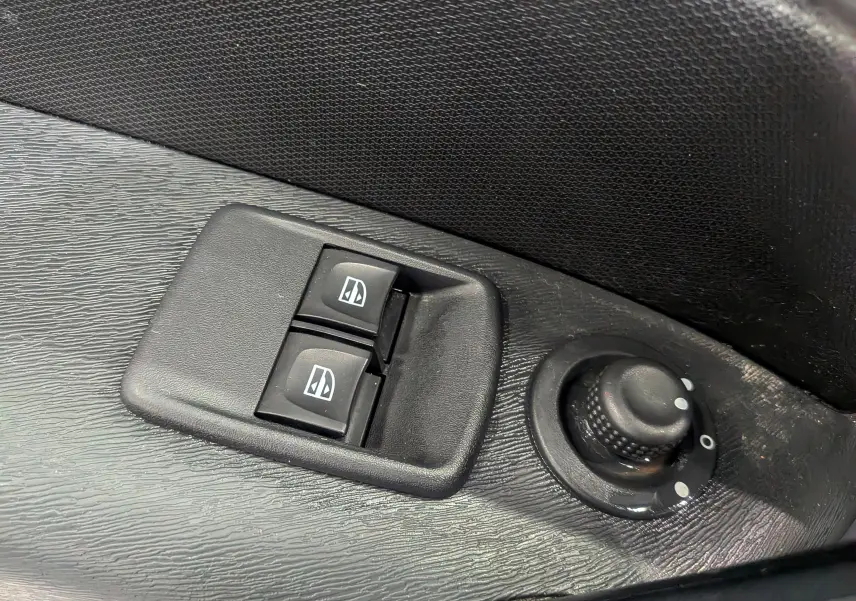 Gros plan sur les commandes électriques des vitres et le réglage des rétroviseurs sur la porte intérieure noire d’un Renault Kangoo Express.