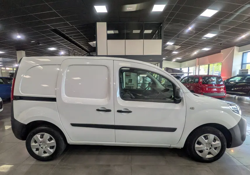 Vue de profil côté droit d’un Renault Kangoo Express blanc minéral, utilitaire compact en showroom lumineux.
