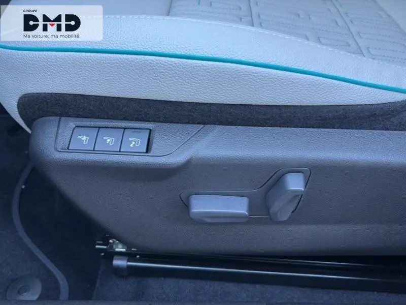 Gros plan sur les commandes de réglage électrique du siège conducteur du FIAT 600 rouge, avec cuir clair et surpiqûres bleues.