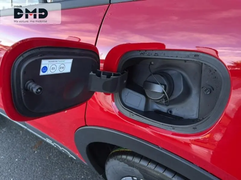 Gros plan sur la trappe à carburant ouverte côté gauche d'une FIAT 600 rouge, avec bouchon essence visible.