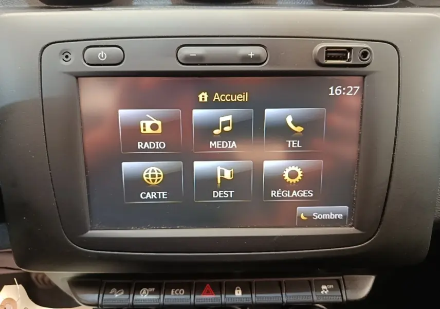 Écran tactile central du tableau de bord du Dacia Duster blanc, affichant le menu principal multimédia.