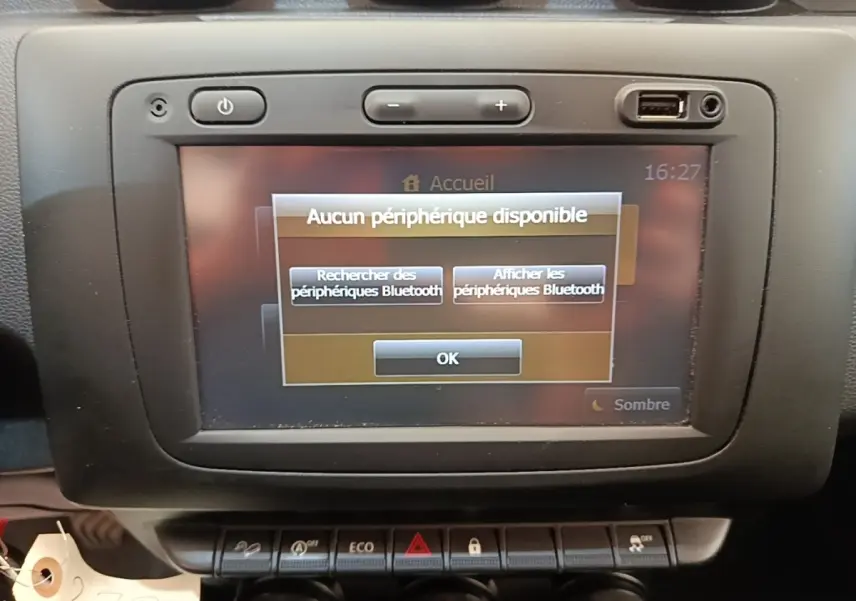 Vue rapprochée de l'écran tactile central du tableau de bord du Dacia Duster blanc, affichant un message Bluetooth.