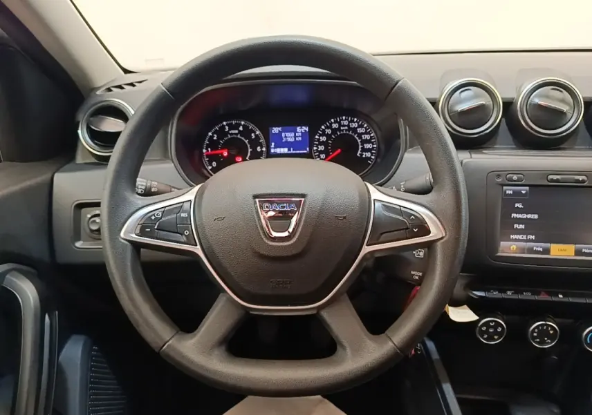 Vue intérieure centrée sur le volant cuir noir du Dacia Duster 2021 avec tableau de bord et écran tactile visible.