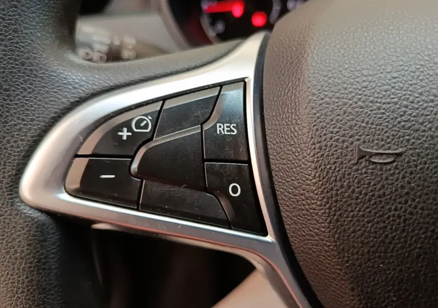 Gros plan sur les commandes du volant cuir synthétique du Dacia Duster 2021, boutons multifonctions visibles.