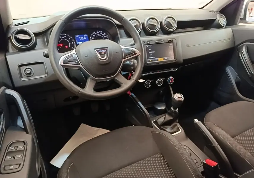 Vue intérieure côté conducteur du tableau de bord et volant cuir synthétique du Dacia Duster blanc de 2021.