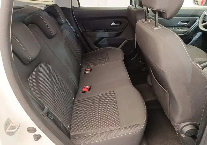 Vue intérieure arrière côté gauche du Dacia Duster blanc, montrant la banquette arrière en tissu noir avec appuie-têtes.
