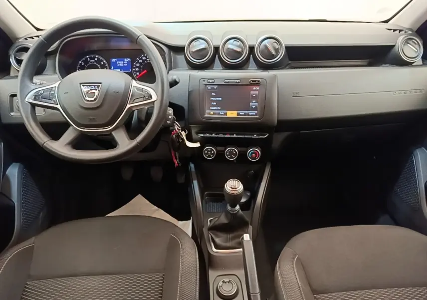 Vue intérieure avant du tableau de bord du Dacia Duster 2021, volant multifonctions et écran tactile central.