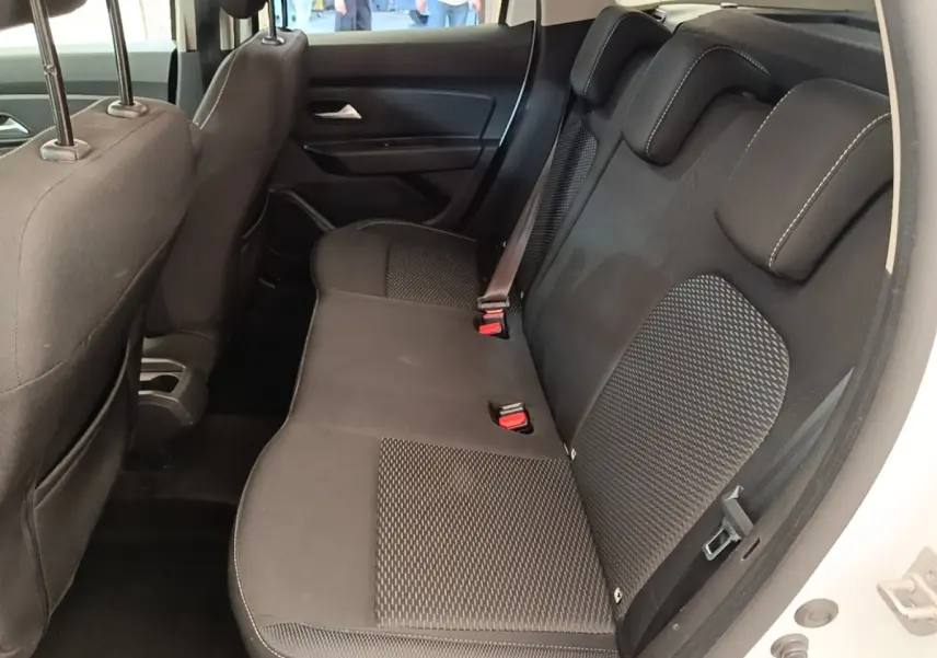 Vue latérale droite de la banquette arrière noire du Dacia Duster blanc, avec ceinture de sécurité visible.