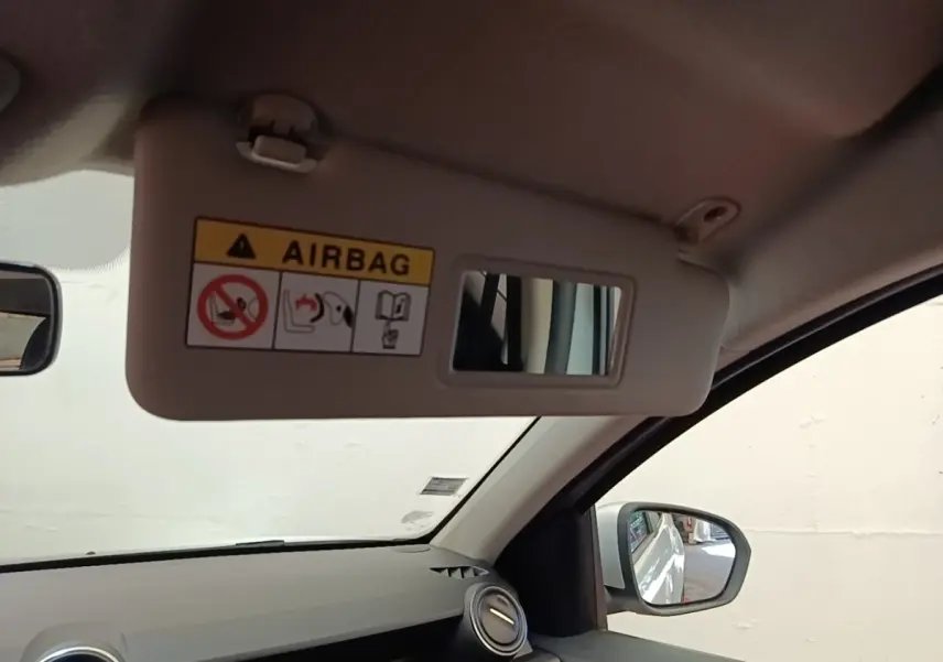Vue intérieure côté conducteur du pare-soleil avec miroir et avertissement airbag du Dacia Duster blanc 2021.