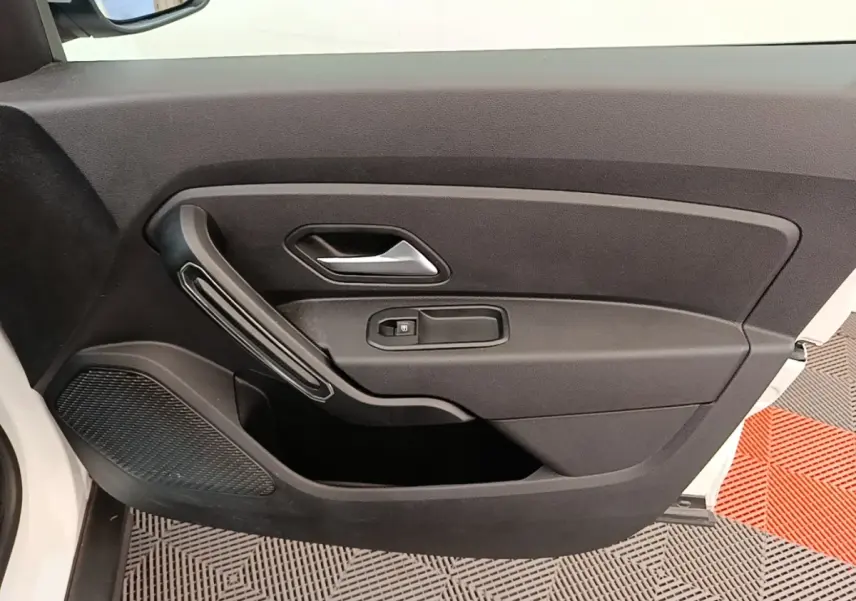 Vue intérieure de la porte avant gauche du Dacia Duster blanc, avec poignée argentée et commande de vitre électrique.