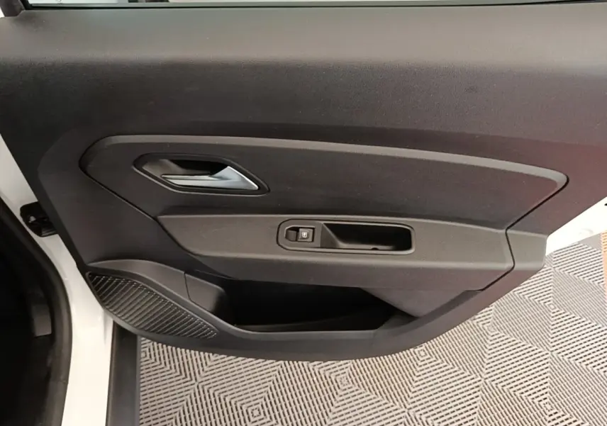 Vue rapprochée de la porte avant gauche blanche du Dacia Duster 2021, avec poignée intérieure et bouton de verrouillage.