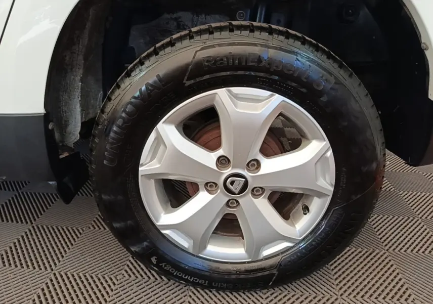 Gros plan sur la roue avant gauche blanche du Dacia Duster avec jante alliage et pneu UniRoyal.