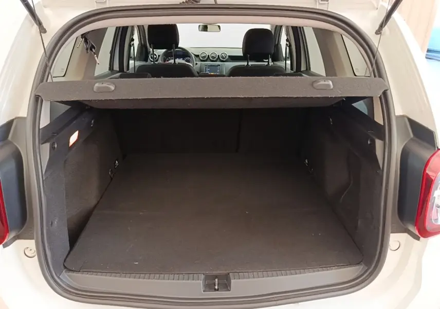Vue arrière du coffre ouvert d'un Dacia Duster blanc 2021, montrant l'espace de chargement et l'intérieur noir.