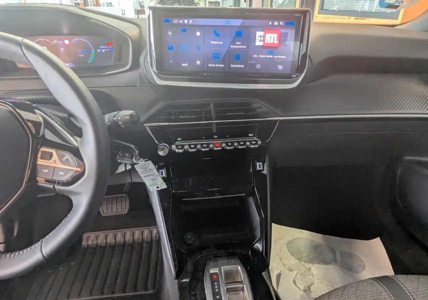 Vue intérieure du tableau de bord du Peugeot 2008 Hybrid 145, avec écran tactile 10 pouces et volant multifonction noir.