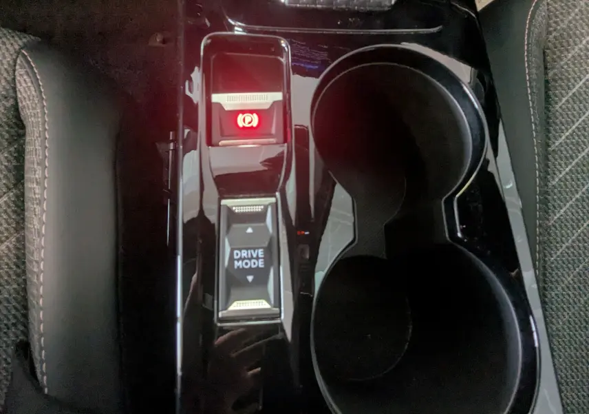 Vue rapprochée du levier de mode de conduite et frein à main électronique sur la console centrale noire du Peugeot 2008 Hybrid 145.