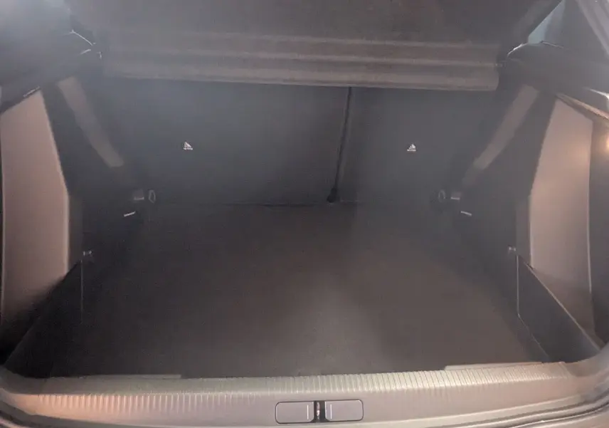 Vue intérieure du coffre spacieux et vide du Peugeot 2008 Hybrid 145 e-DCS6 Allure, avec revêtement noir.