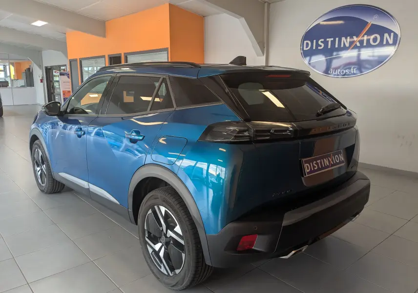 Vue 3/4 arrière droite du Peugeot 2008 Hybrid 145 bleu Obsession avec jantes alliage 17'' et vitres surteintées en showroom.