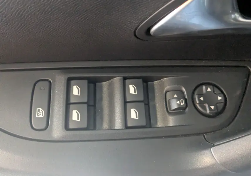 Gros plan sur les commandes de lève-vitres et réglage des rétroviseurs côté conducteur du Peugeot 2008 Hybrid 145 bleu Obsession.