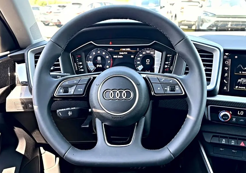 Vue frontale du volant cuir multifonction noir et du tableau de bord numérique de l'Audi A1 Sportback blanc/noir.