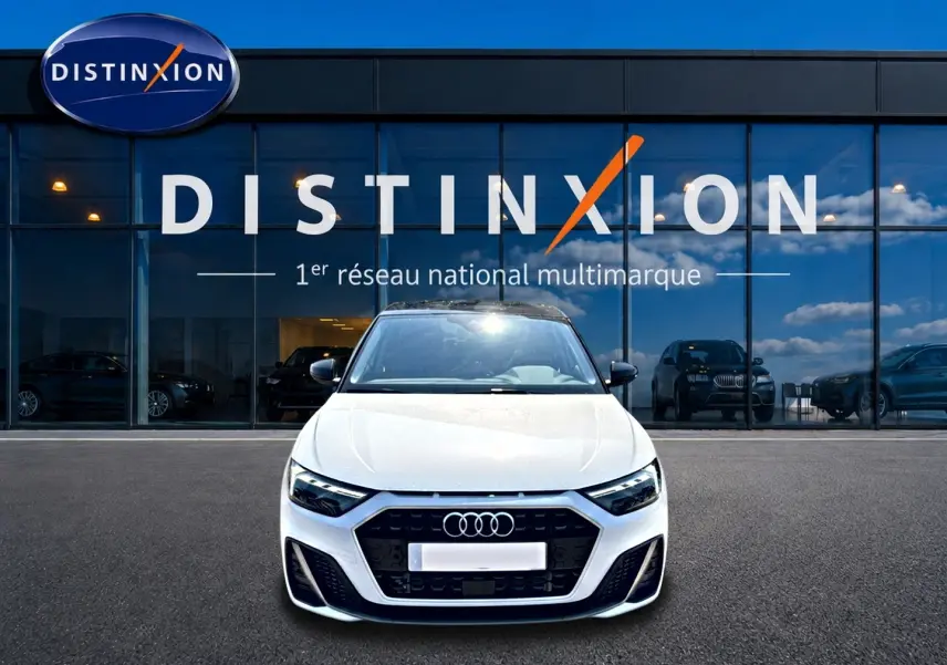 Audi A1 Sportback blanc et noir vue de face, avec calandre noire et logo Audi devant un showroom Distinxion.