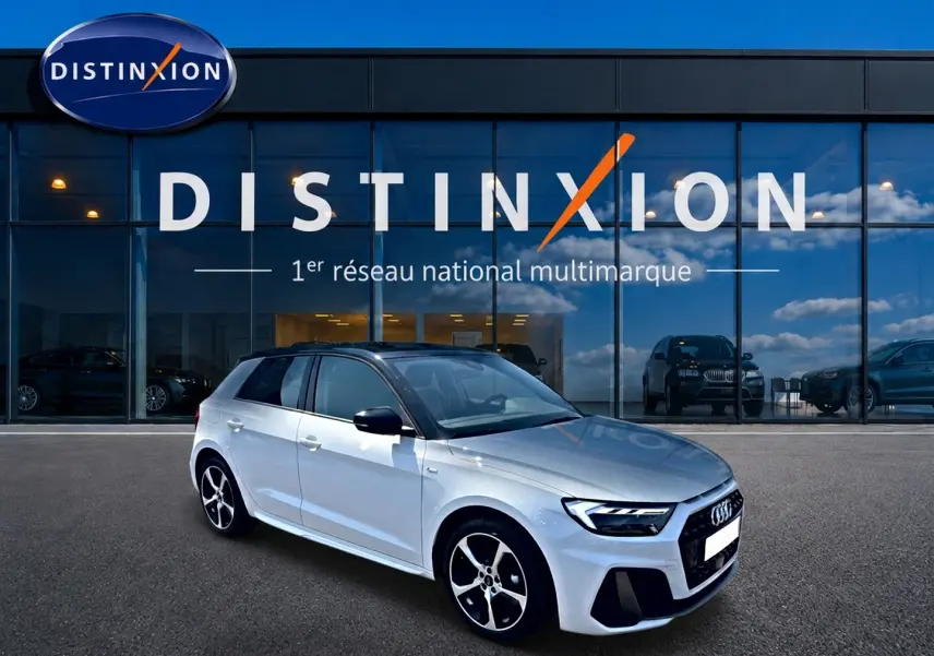 Audi A1 Sportback blanc et noir vue 3/4 avant droit devant un showroom Distinxion avec jantes alu distinctives.