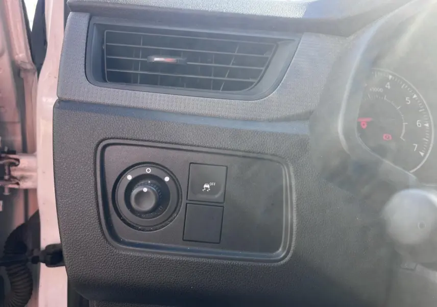 Détail du tableau de bord noir côté gauche avec commande des phares et bouton de désactivation de l'ESP sur Renault Express Van blanc.