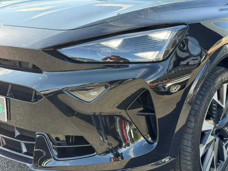 Gros plan sur l'avant droit du CUPRA Formentor 2025 noir Minuit métallisé, mettant en valeur le phare LED et la calandre sportive.