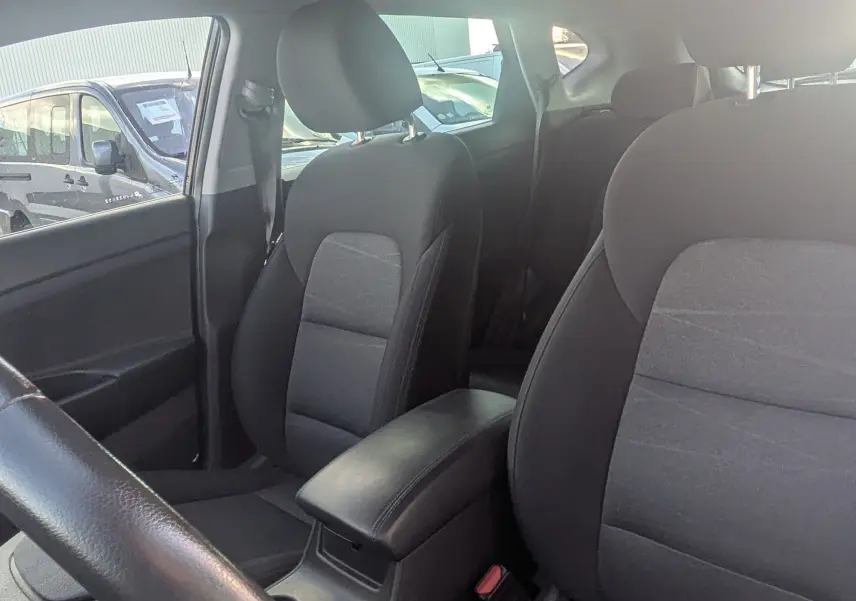 Vue intérieure côté conducteur du Hyundai Tucson 2019, sièges noirs avec clé de contact posée sur le siège avant.