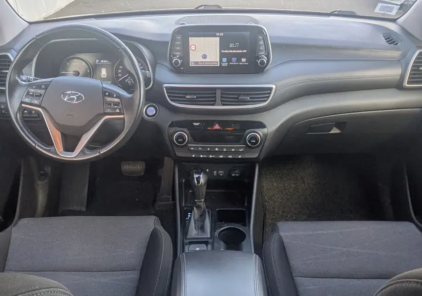 Vue intérieure avant du Hyundai Tucson noir 2019, mettant en valeur le tableau de bord avec écran tactile et volant multifonction.